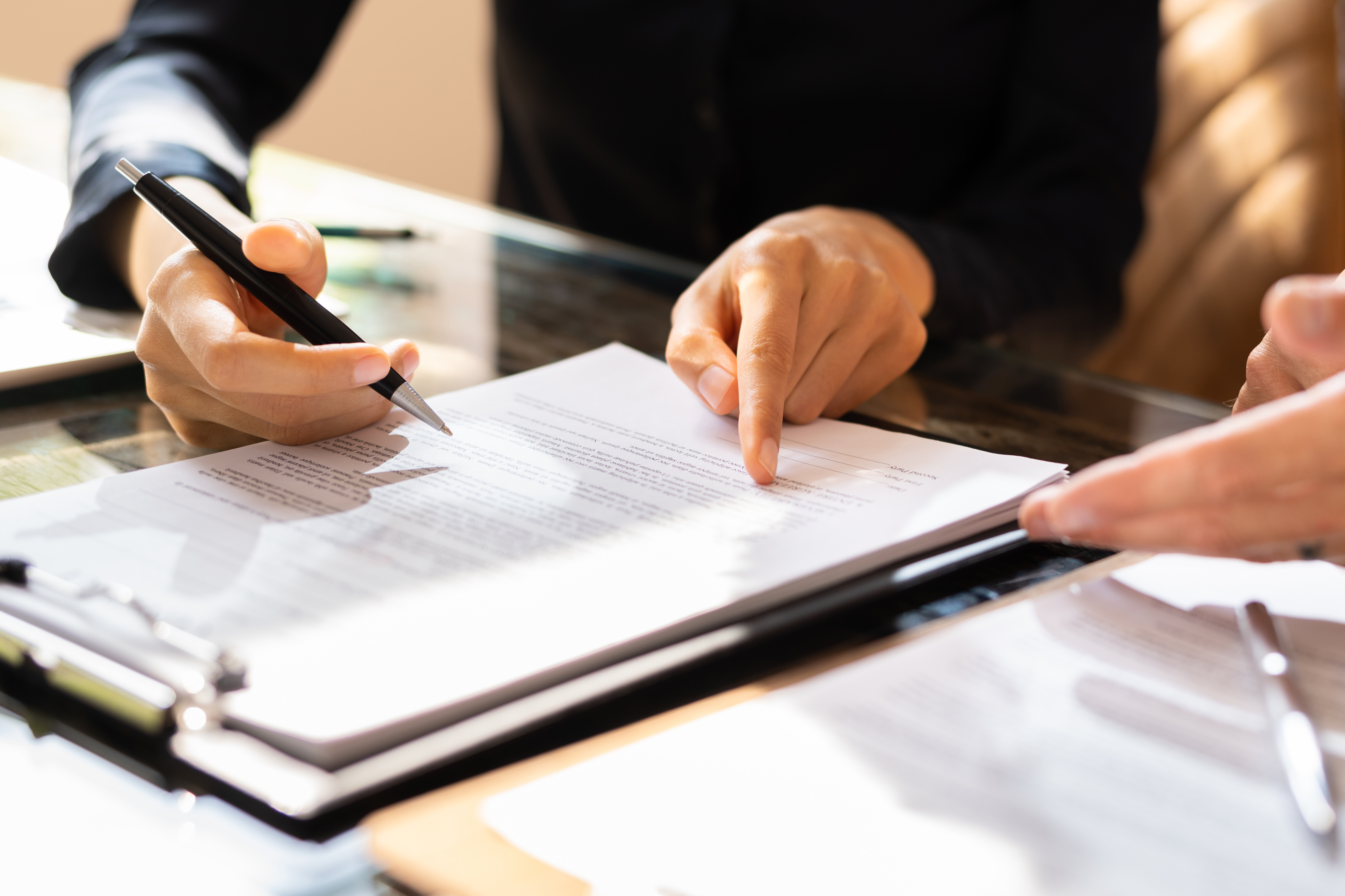 Hands pointing to a specific paragraph on a printed contract-style record page