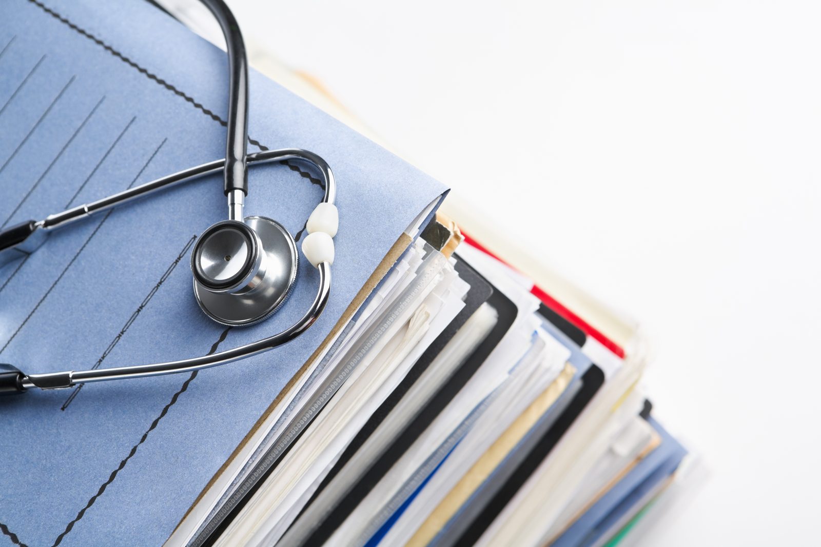 A stethoscope resting on stacked medical record files